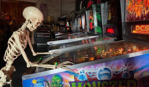 A skeleton plays a pinball machine in the arcade at the Graveface Museum